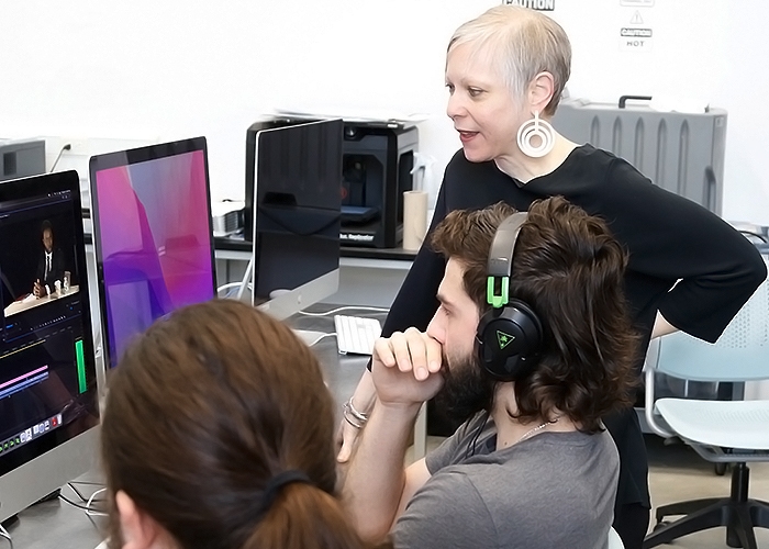 Professor looks on while student filmmakers edit film