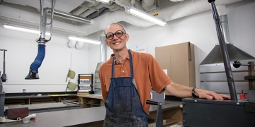 Professor of Art Stephen Fisher poses in RIC's Alex and Ani Hall's printmaking studio.