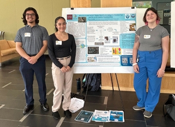 Biology research students standing near presentation board