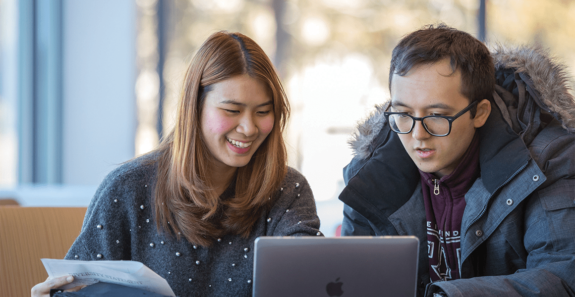 Two students working on a laptop