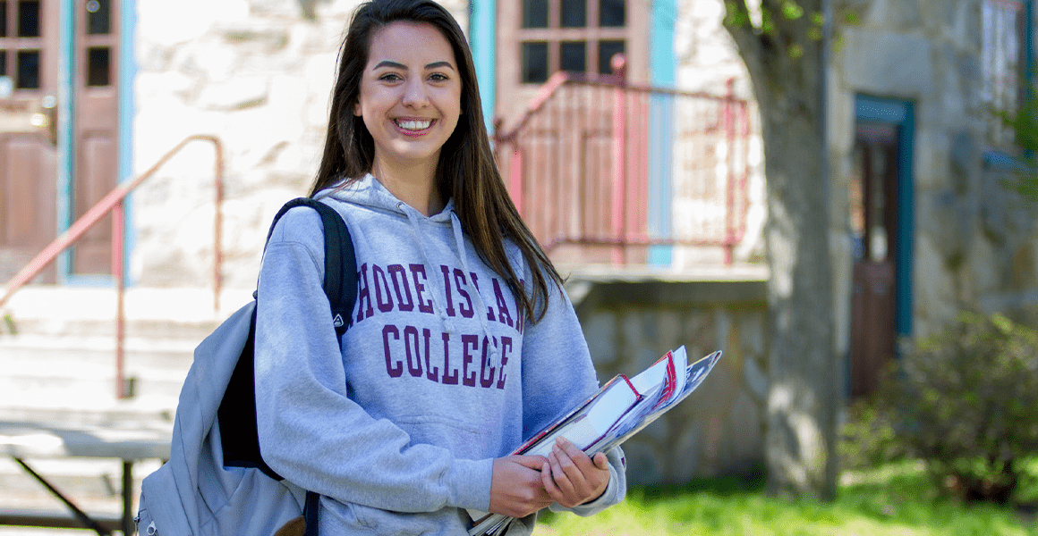 Student in RIC sweatshirt outside Roberts Hall 