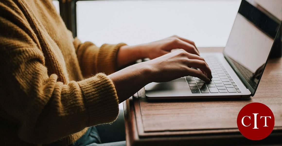 Person typing at laptop, with CIT logo in corner
