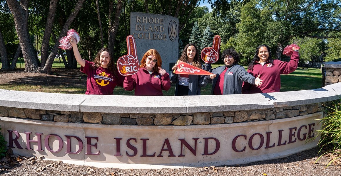 Admissions Counselors showing their RIC pride by campus main entrance