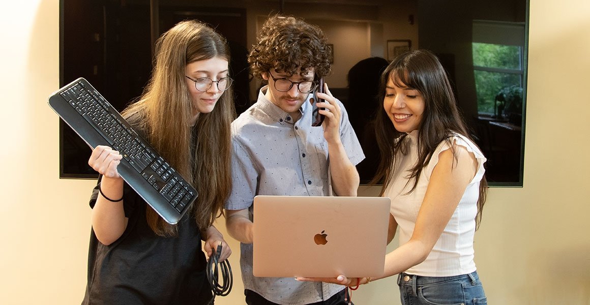 Helpdesk team working on laptop, phone, and with other tech
