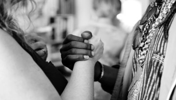 Two interracial people holding hands in solidarity