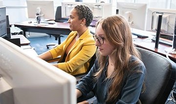 Two female student working at computers in the finance lab