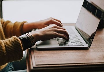 Person's hands typing on laptop