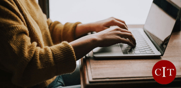 Person sitting at laptop, typing, with CIT logo in corner
