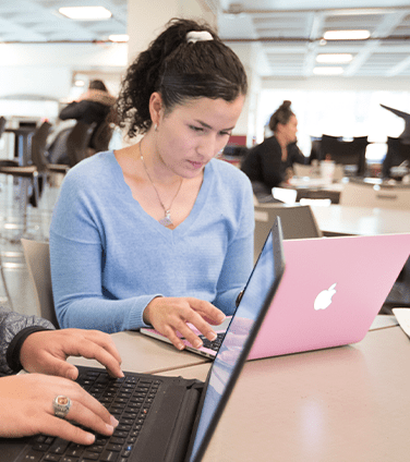 Female student working on a pink laptop in the Donovan dinning center 