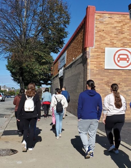 A group of students walk up Broad Street, facing away from the camera, for a class tour