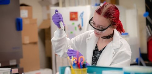 Female inserting a liquid into a container in science lab