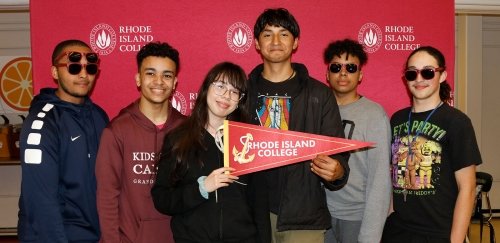 Central Falls students pose for a photograph, holding up a RIC flag of an anchor