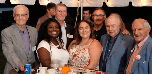 Seven alumni looking at the camera for a picture at an alumni event