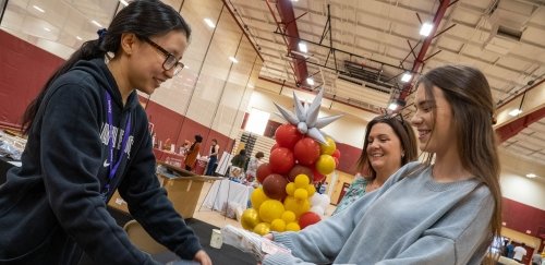 Student receives materials from person at Grad Fest