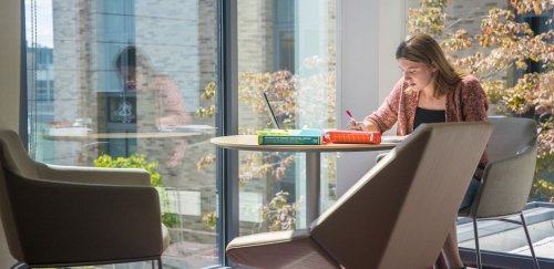 Student studying in lobby of Craig Lee Hall by windows