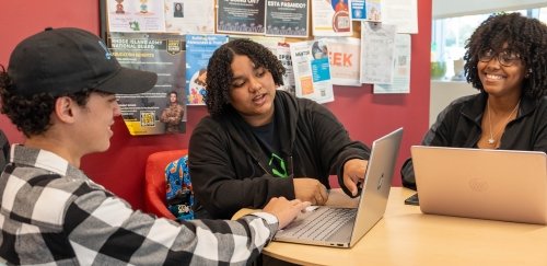 Students working at a table on laptops together in the Center for Scholar Development