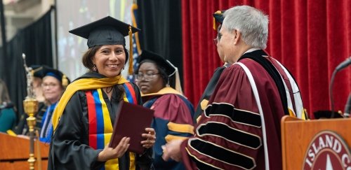 Graduate student being handed diploma from President Warner