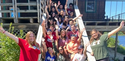 Group of RIC students smiling and waving on the steps on a sunny day