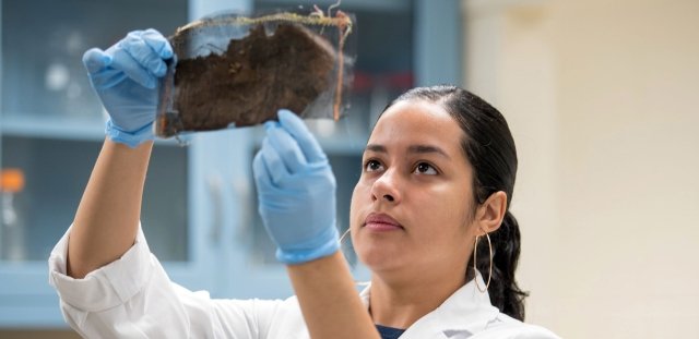 Student holding up bag of soil