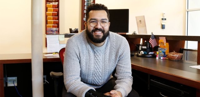 Steven Pina leans forward in chair and smiles