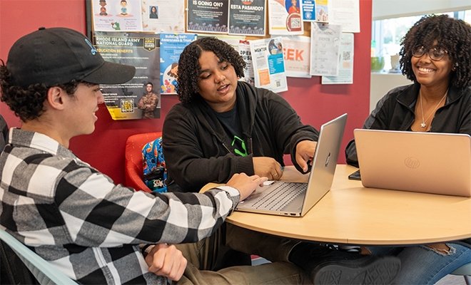 Students working on laptops at tables in the Center for Scholar Development