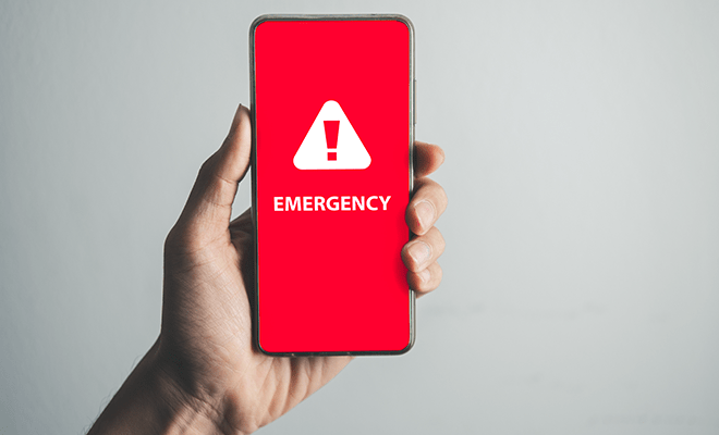 Hand holding phone with emergency notification showing